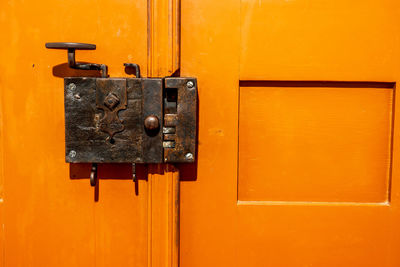 Old door lock on orange wooden door