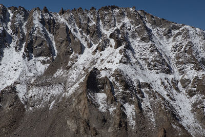 Low angle view of icicles on rock against snowcapped mountains