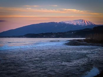 Scenic view of sea and mountains against sky during sunset