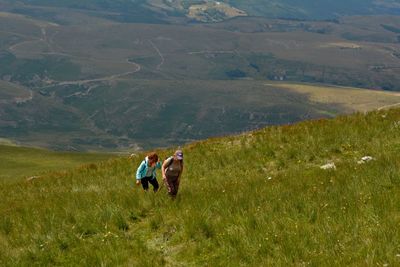 Rear view of people on field against mountain