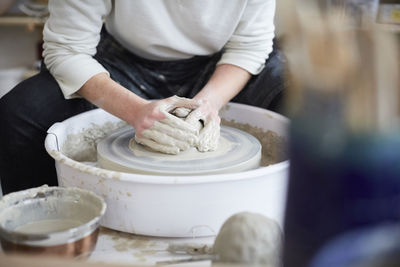 Midsection of woman molding pot in pottery class