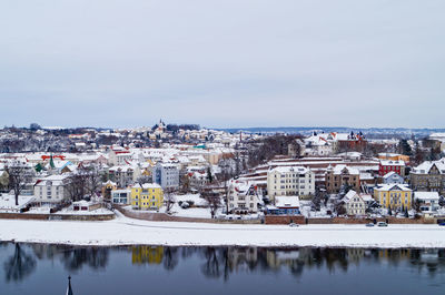 Snow covered meissen townscape by lake against sky during winter