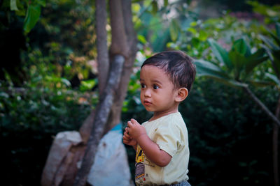 Cute boy looking away while standing outdoors