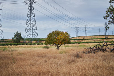 Electricity pylon on field against sky