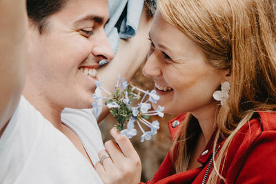 Close-up of smiling woman holding flowers by man