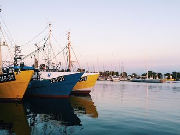 Sailboats moored on harbor against clear sky