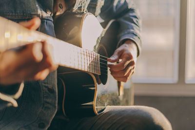 Midsection of man playing guitar