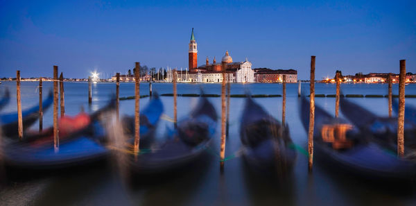 Long exposure of gondolas moored on canal against sky