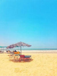 Deck chairs on beach against clear blue sky