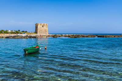 Boat in sea against clear blue sky