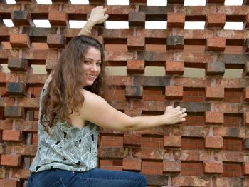 Portrait of smiling woman standing against brick wall