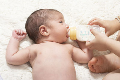 Cute baby drinking milk while lying on floor at home