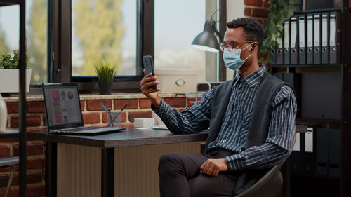 Young businessman wearing mask while talking on video call