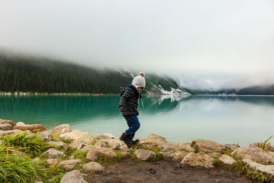 Boy walking at lakeshore against sky