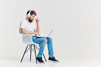 Full length of man sitting on chair against white background