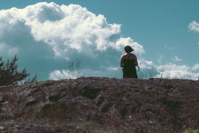 Rear view of a man standing on landscape against sky