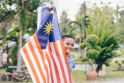 Portrait of smiling boy holding malaysian flag