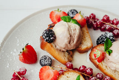 Close-up of ice cream with fruits and breads in plate on table