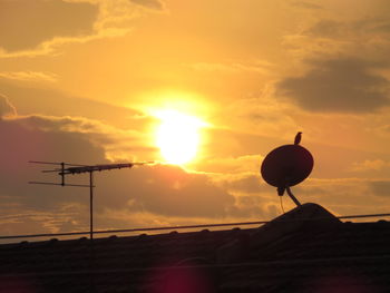 Low angle view of silhouette telephone against sky during sunset