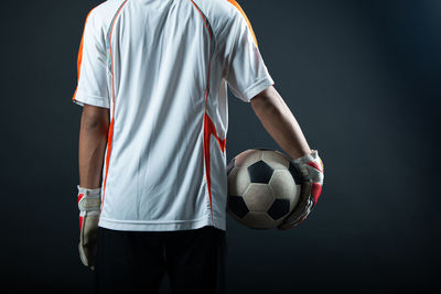 Low angle view of man playing soccer against black background