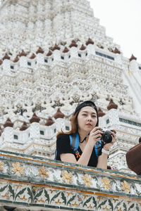 Low angle view of woman looking away against building