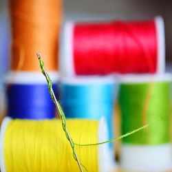 Close-up of needle with thread against spools