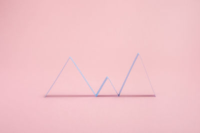 Creative abstract geometric zig zags lines arranged in chart pattern placed on pink background with shadow in light modern studio