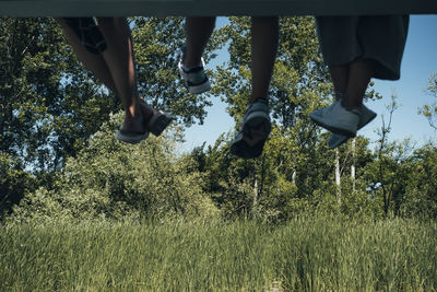 Low section of woman walking on street amidst trees