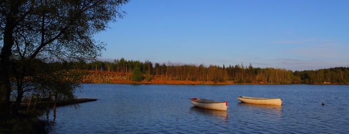 Boats in lake against clear sky