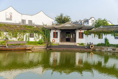 Houses by lake and buildings against sky