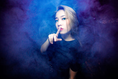 Portrait of a young woman smoking over black background