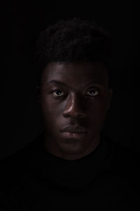 Close-up portrait of young man against black background