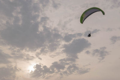 Low angle view of person paragliding against sky