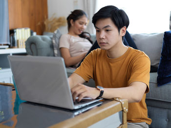 Couple using laptop while sitting at home