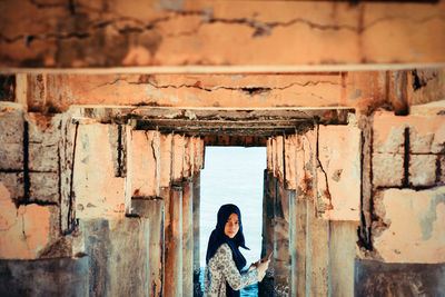 Portrait of woman standing below abandoned pier