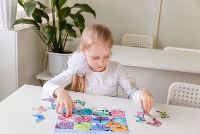 A girl student sits at a desk in the classroom and collects figures / puzzles / small toys 