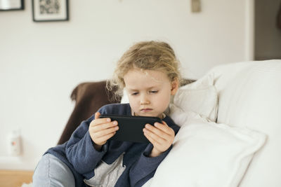 Girl using mobile phone on sofa at home