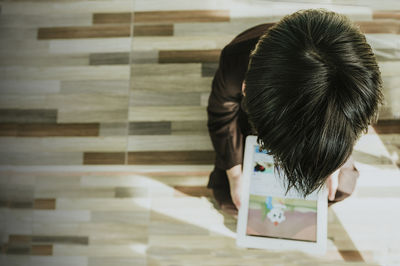 Directly above shot of boy using digital tablet on parquet floor at home