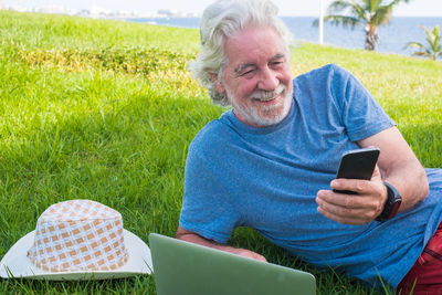 Portrait of man using mobile phone in grass