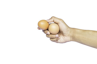 Close-up of hand holding apple against white background