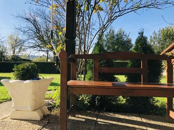 Empty bench in park against clear sky