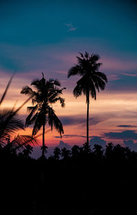 Silhouette palm trees against romantic sky at sunset