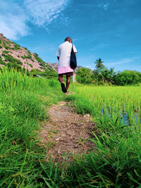 Rear view of man walking on field