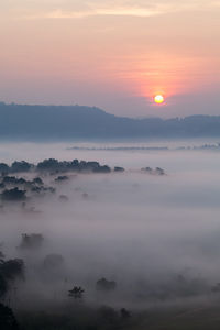 Scenic view of foggy landscape during sunset