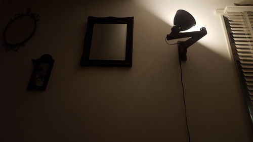 Low angle view of illuminated lighting equipment hanging against wall