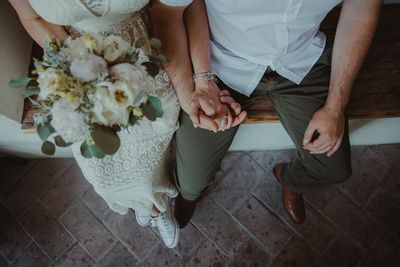 Low section of couple holding hands during wedding ceremony