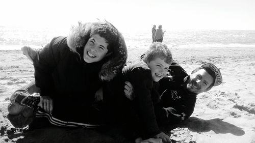 Portrait of happy friends standing on beach during winter