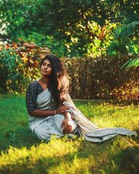 Beautiful young woman sitting on land