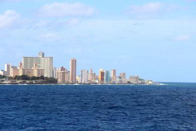 Sea by cityscape against sky