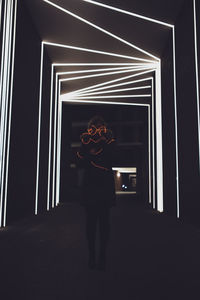 Rear view of woman standing against illuminated building